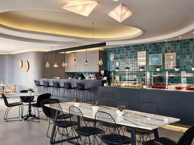 Moderne hotel lounge met bar, zitplaatsen en stijlvolle verlichting.