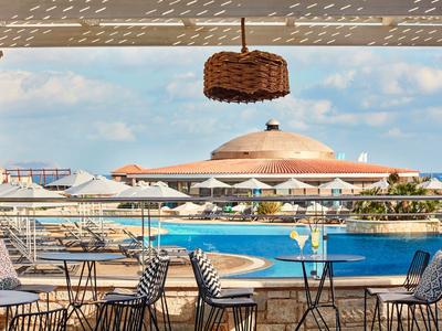 Pohled na bazén se stoly a židlemi pod zastřešenou plochou v hotelu.