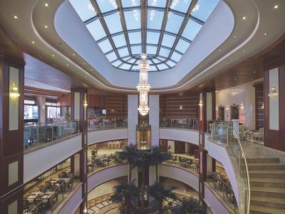 Lichte hotellobby met groot glazen dak en atrium over twee verdiepingen.