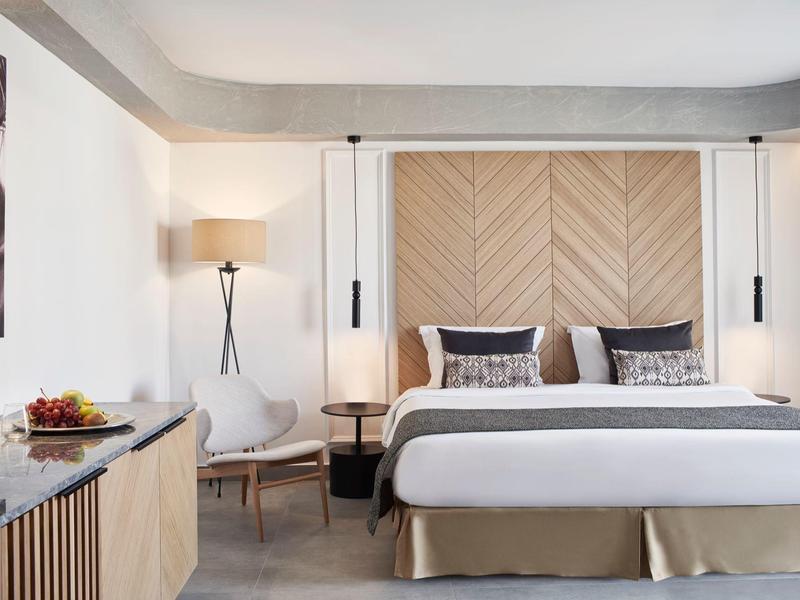 Moderne slaapkamer met groot bed, houten accenten en gezellige zitgelegenheid.