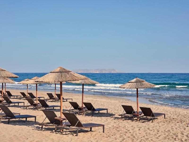 Strand met parasols en ligstoelen bij de zee onder een heldere lucht.