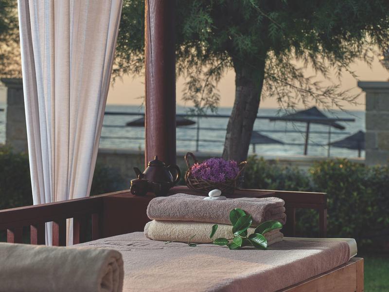 Gezellige buitenligstoel met schone handdoeken en bloemen naast een boom in de tuin.