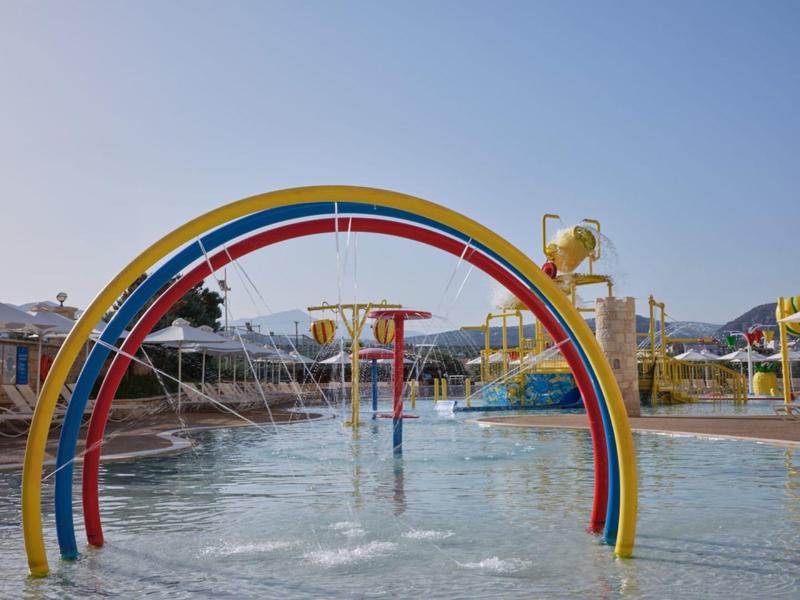 Kleurrijke waterspeelplaats met felle bogen en watersproeiers onder heldere hemel.