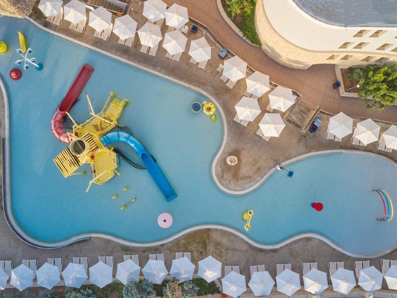 Luchtfoto van een hotelzwembad met glijbanen en ligstoelen.