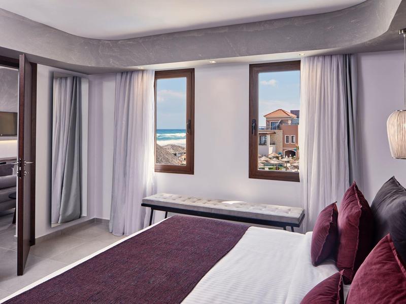 Slaapkamer met zeezicht, moderne meubels en paarse accenten.