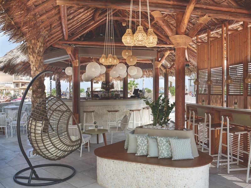 Gezellige lounge met hangstoel en bar in een open tropisch houten gebouw