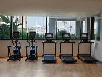 Moderne fitnessruimte met loopbanden en crosstrainers voor grote ramen met uitzicht op het terras buiten.