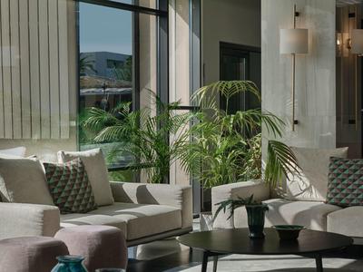 Chambre d'hôtel lumineuse avec canapé, plantes et table basse moderne.