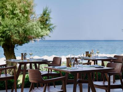 Terrasse extérieure avec tables et chaises donnant sur la mer sous un ciel dégagé.