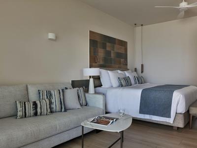 Camera d'hotel moderna con grande letto, divano e tavolino.