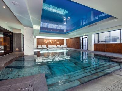 Piscine intérieure moderne avec cascade et grandes fenêtres dans un hôtel.