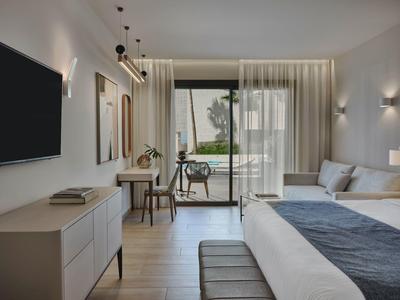 Chambre d'hôtel moderne avec lit double, bureau, TV et balcon avec vue sur la verdure.