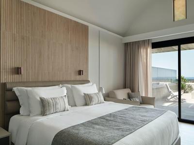 Chambre d'hôtel moderne avec grand lit, panneau en bois et terrasse vue mer.