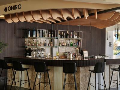 Espace bar d'hôtel moderne avec décoration en bois ondulé et tabourets hauts.