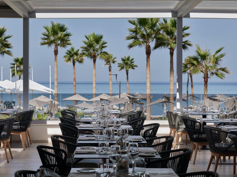 Restaurant de plage avec tables dressées et vue sur la mer et les palmiers