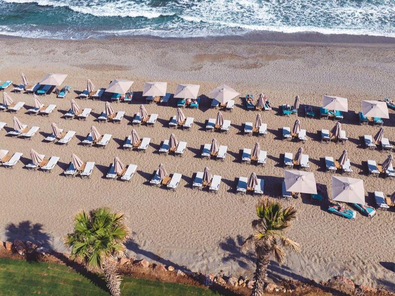 Rangées de chaises longues et parasols sur la plage face à la mer.