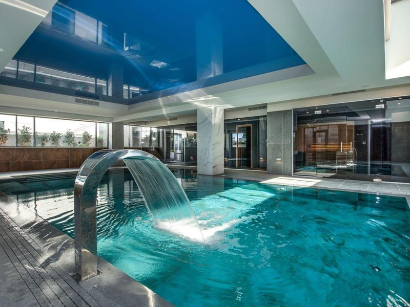 Piscine intérieure moderne avec eau claire, élément d'eau et fenêtres en verre dans un hôtel.