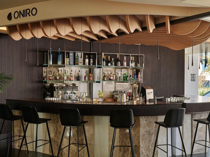 Espace bar d'hôtel moderne avec décoration en bois ondulé et tabourets hauts.