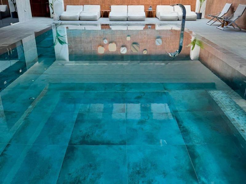 Piscine intérieure moderne avec grand jacuzzi et ambiance lounge détendue.