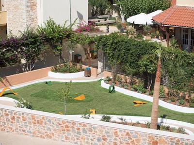 Grüner Garten mit Trampolin, Sandkasten, Bäumen und umgebender Mauer in Wohnanlage.