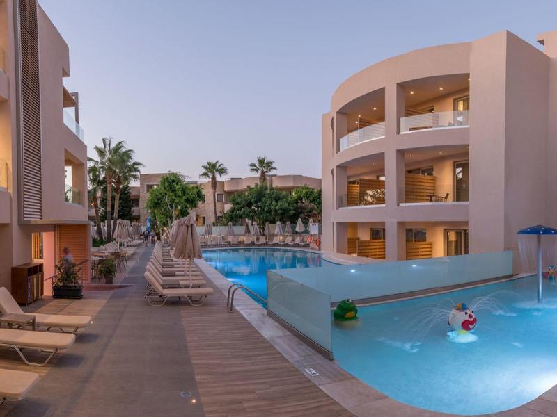 Complex avec piscine éclairée et chaises longues le long du chemin au crépuscule