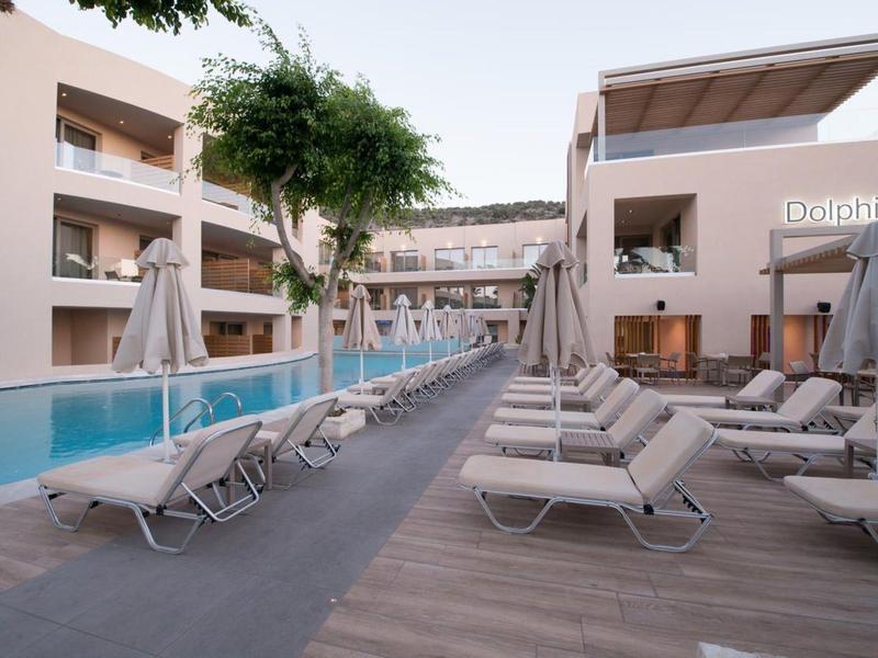 Espace piscine extérieur d'hôtel avec chaises longues et parasols entre deux bâtiments.