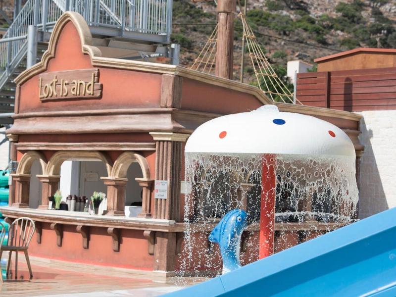 Zone de piscine extérieure avec un parasol d'eau et un bar en bois nommé Lokomotiva.