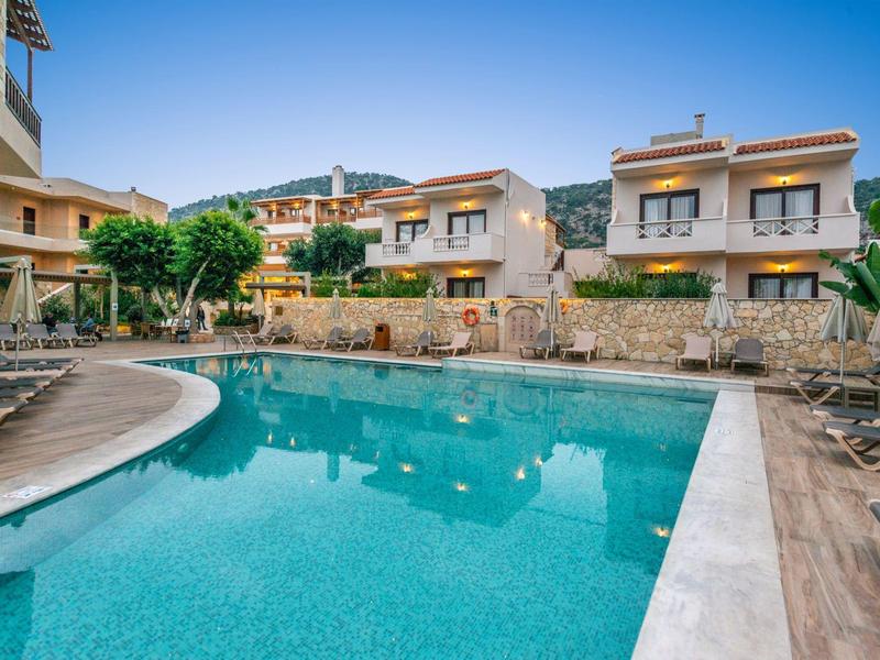 Piscine extérieure avec chaises longues et parasols dans un complexe hôtelier en journée.