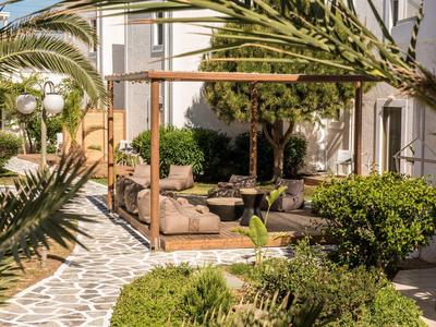 Gemütliche Terrasse mit gepolsterten Sitzkissen, umgeben von Palmen und grünem Strauchwerk.