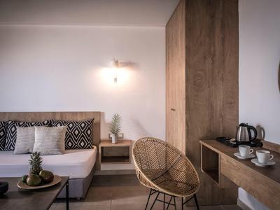 Helles Wohnzimmer mit weißem Sofa, Holzmöbeln, Rattanstuhl und minimalistischer Dekoration.