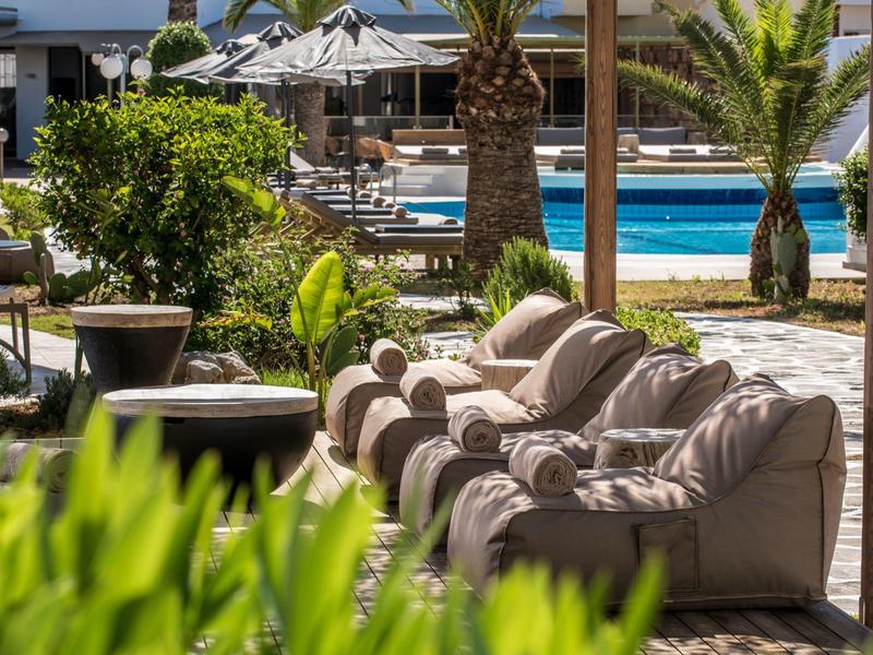 Muebles cómodos con vista a una piscina en un entorno hotelero tropical.