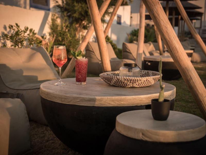 Lounge acogedora con mesa redonda, sillas y bebidas bajo una luz cálida y tenue.