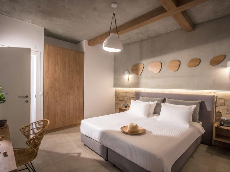 Habitación de hotel moderna con cama doble, muebles de madera y luz cálida.