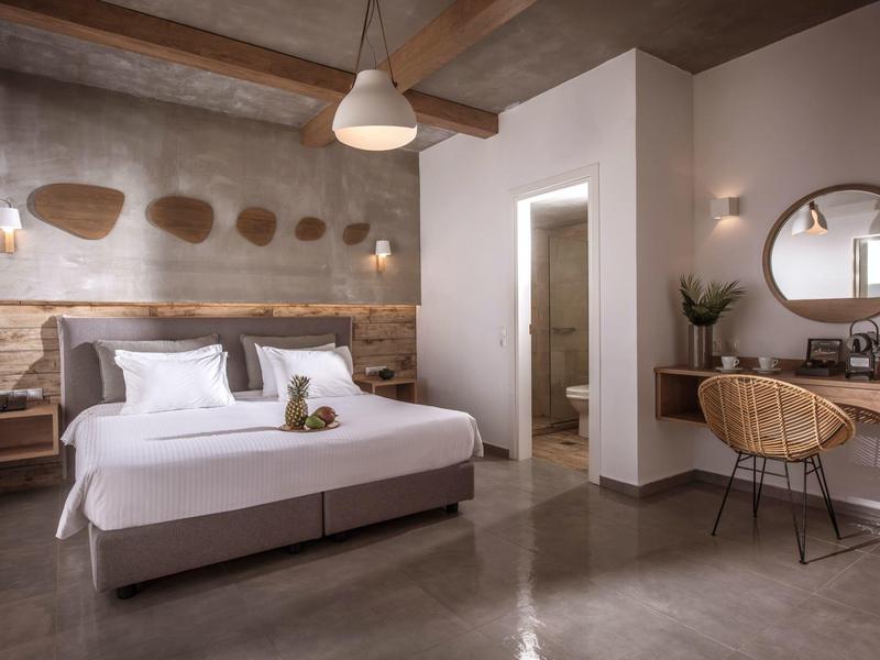Habitación de hotel moderna con cama doble, techo de madera, cestas decorativas y escritorio con silla.