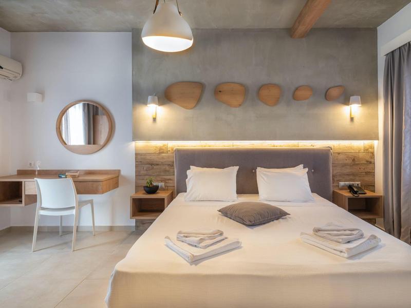 Habitación de hotel moderna con cama doble, escritorio, espejo y cuencos de madera decorativos en la pared.