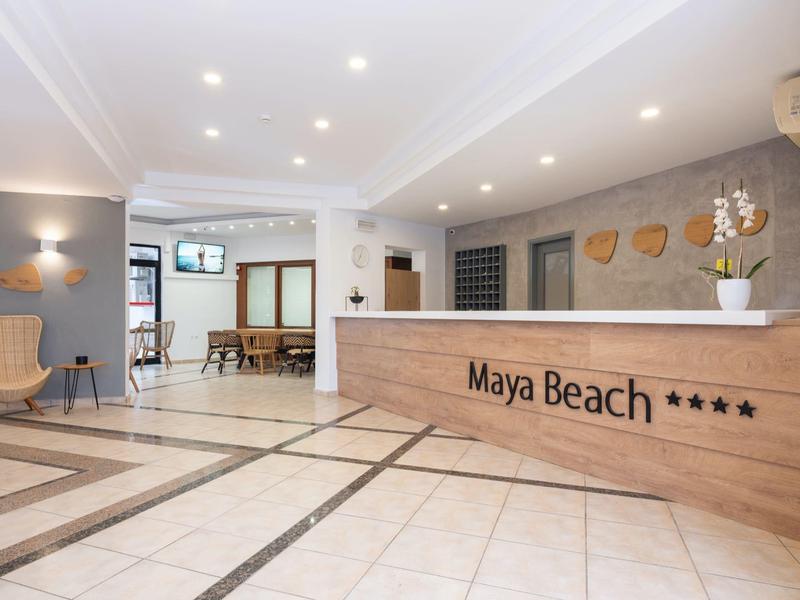 Recepción moderna y luminosa del hotel Maya Beach con mostrador de madera y área de espera elegante.