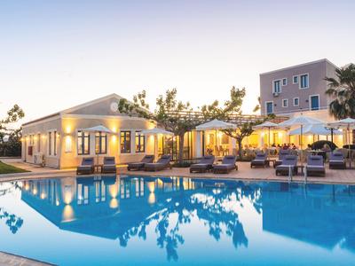 Hotel s bazénem, lehátky a slunečníky při západu slunce.