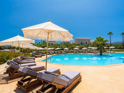 Bazénová oblast s lehátky a slunečníky za jasné oblohy v hotelovém resortu.