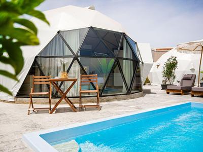 Moderní skleněný pavilon s bazénem a slunečníky na terase.