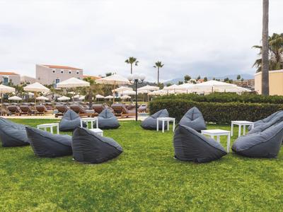 Moderní sedací vaky v hotelové zahradě s deštníky a palmami na pozadí.