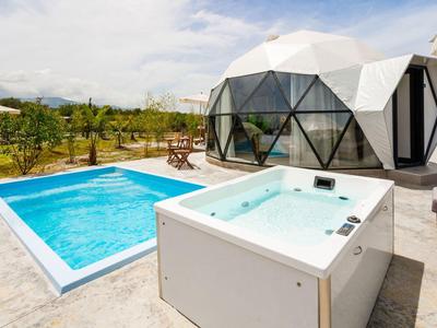 Nowoczesny bungalow z szklaną kopułą z jacuzzi i basenem na zewnątrz.