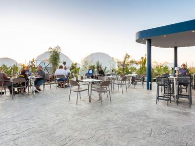 Taras z stołami i krzesłami obok namiotów kopułowych w hotelu o zachodzie słońca.