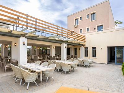 Nowoczesne patio hotelowe z zewnętrznym miejscem do jedzenia i wygodnymi krzesłami pod błękitnym niebem.