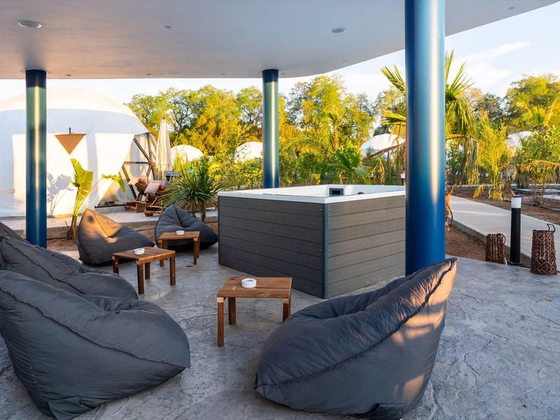 Zadaszony taras z workami sako, jacuzzi i zielonym otoczeniem w ośrodku wypoczynkowym.