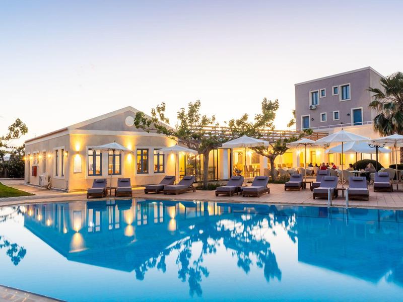 Oświetlony hotel z basenem na zewnątrz i leżakami o zmierzchu
