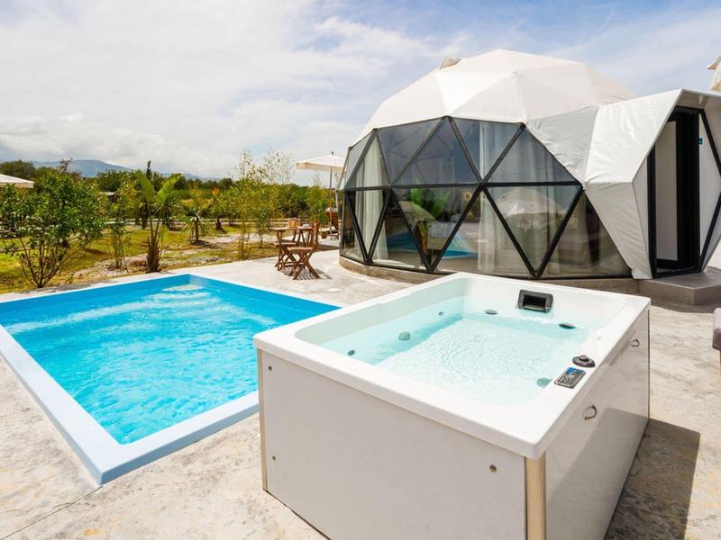 Nowoczesny bungalow z szklaną kopułą z jacuzzi i basenem na zewnątrz.