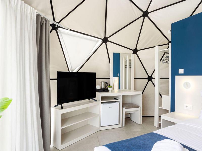 Nowoczesny pokój hotelowy w niebiesko-białym wystroju, telewizorem i biurkiem w kopułowej konstrukcji.