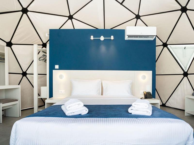 Nowoczesny pokój hotelowy z kopułowym sufitem, podwójnym łóżkiem i niebieską ścianą akcentową