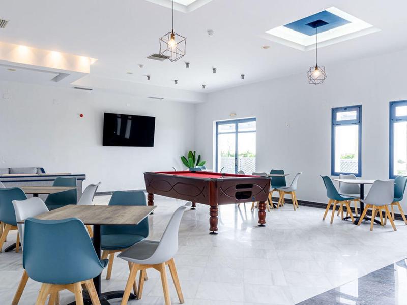 Nowoczesna, jasna sala ogólnodostępna z stołem bilardowym, miejscami do siedzenia i oknami z naturalnym światłem.