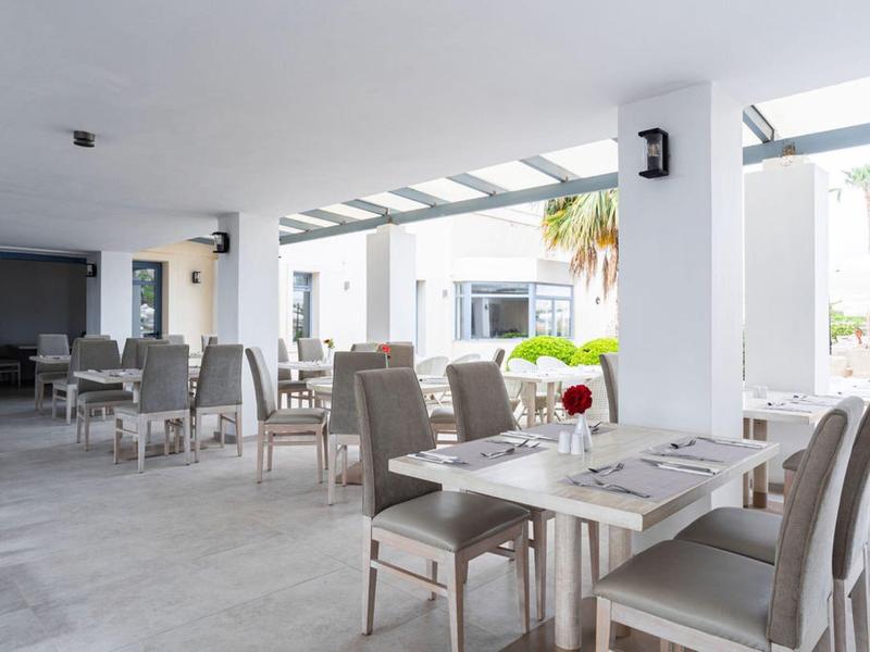 Jasny taras hotelowy z przygotowanymi stołami i nowoczesnymi krzesłami pod szklanym dachem.